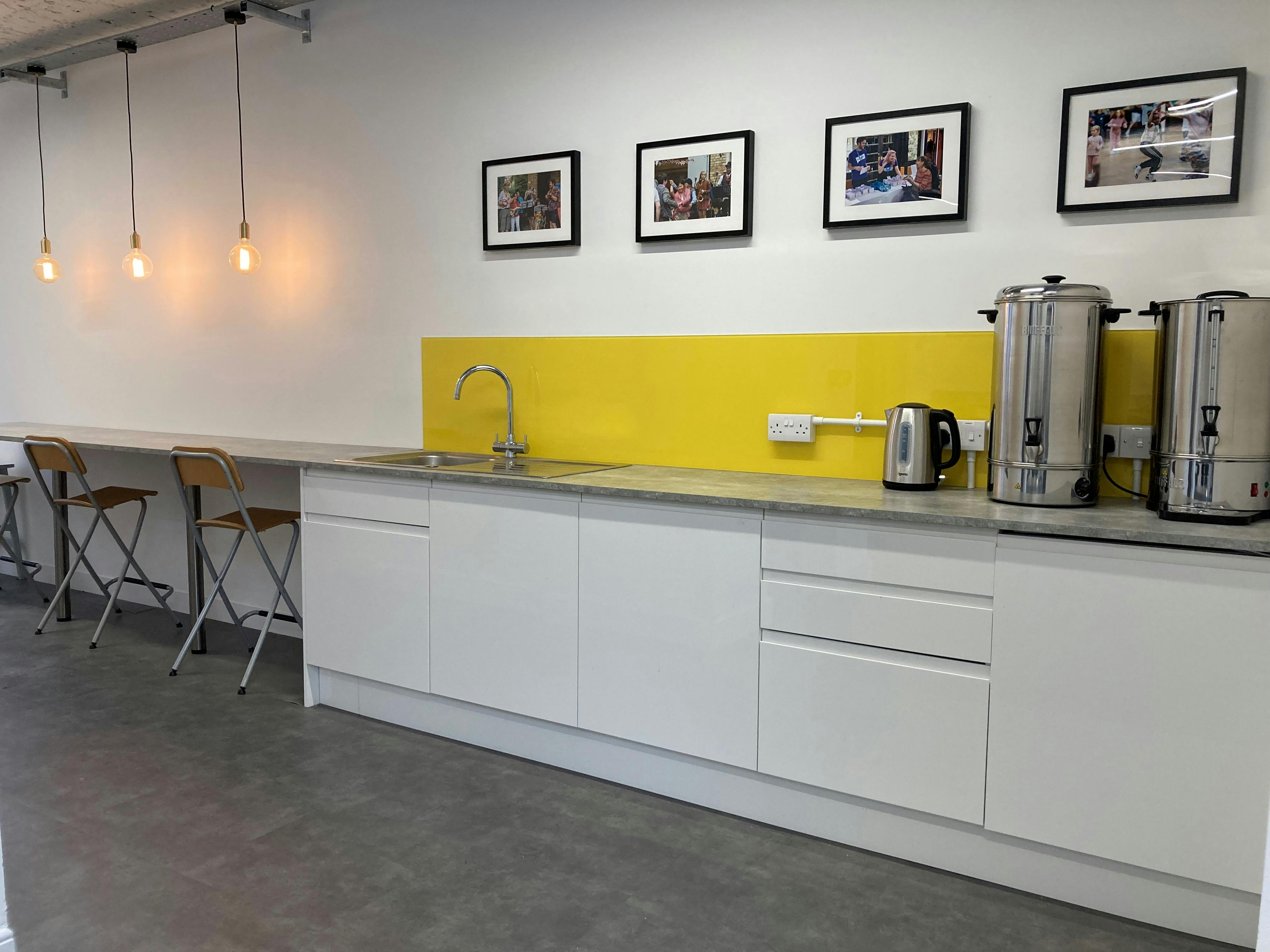 Modern kitchenette with yellow backsplash for meetings and events, ideal for catering breaks.