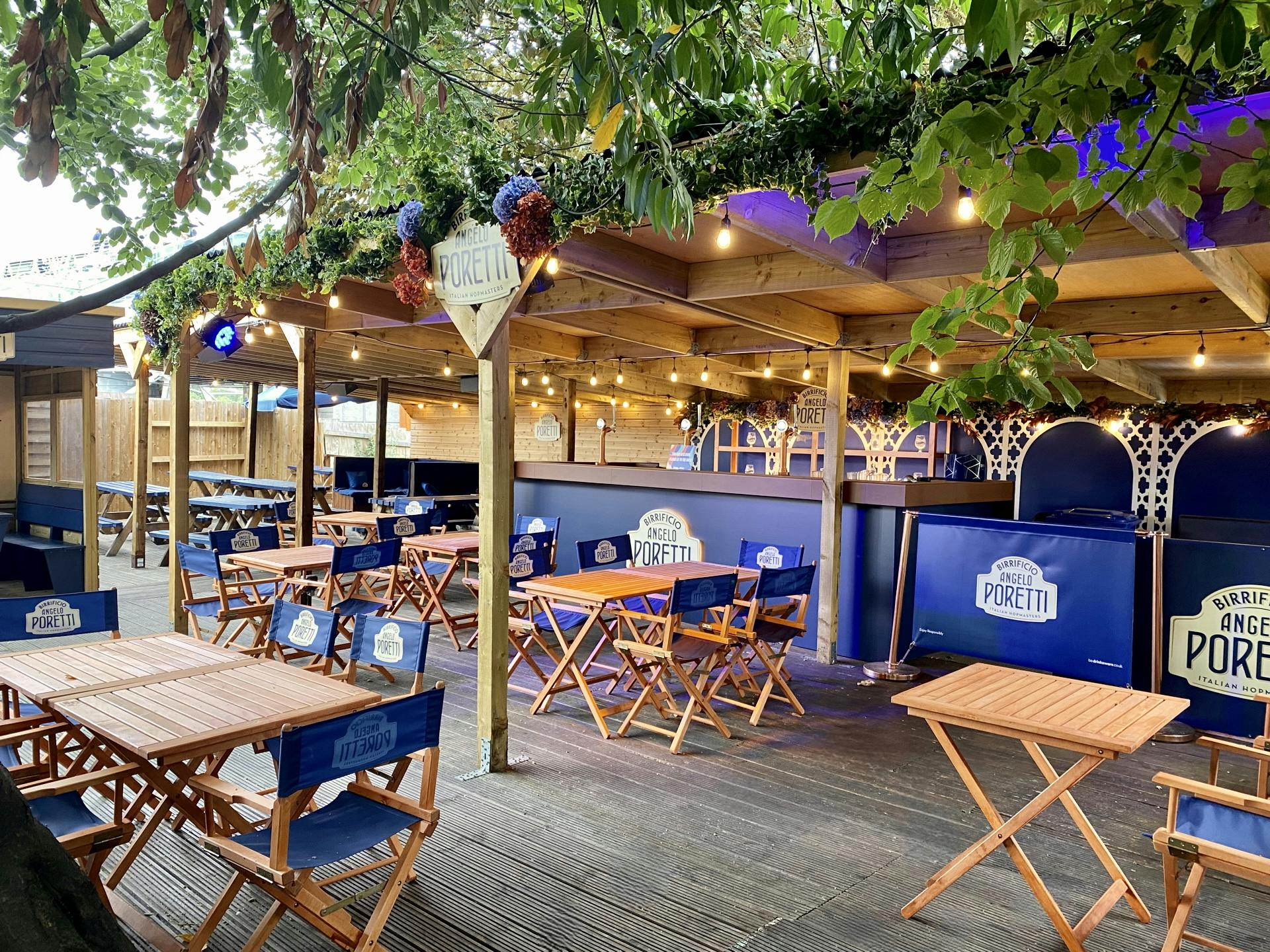 Charming outdoor event space with wooden tables, ideal for casual gatherings and networking.