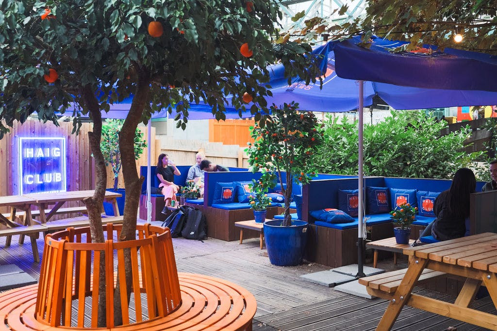 Vibrant outdoor event space with cozy seating under colorful canopies for gatherings.