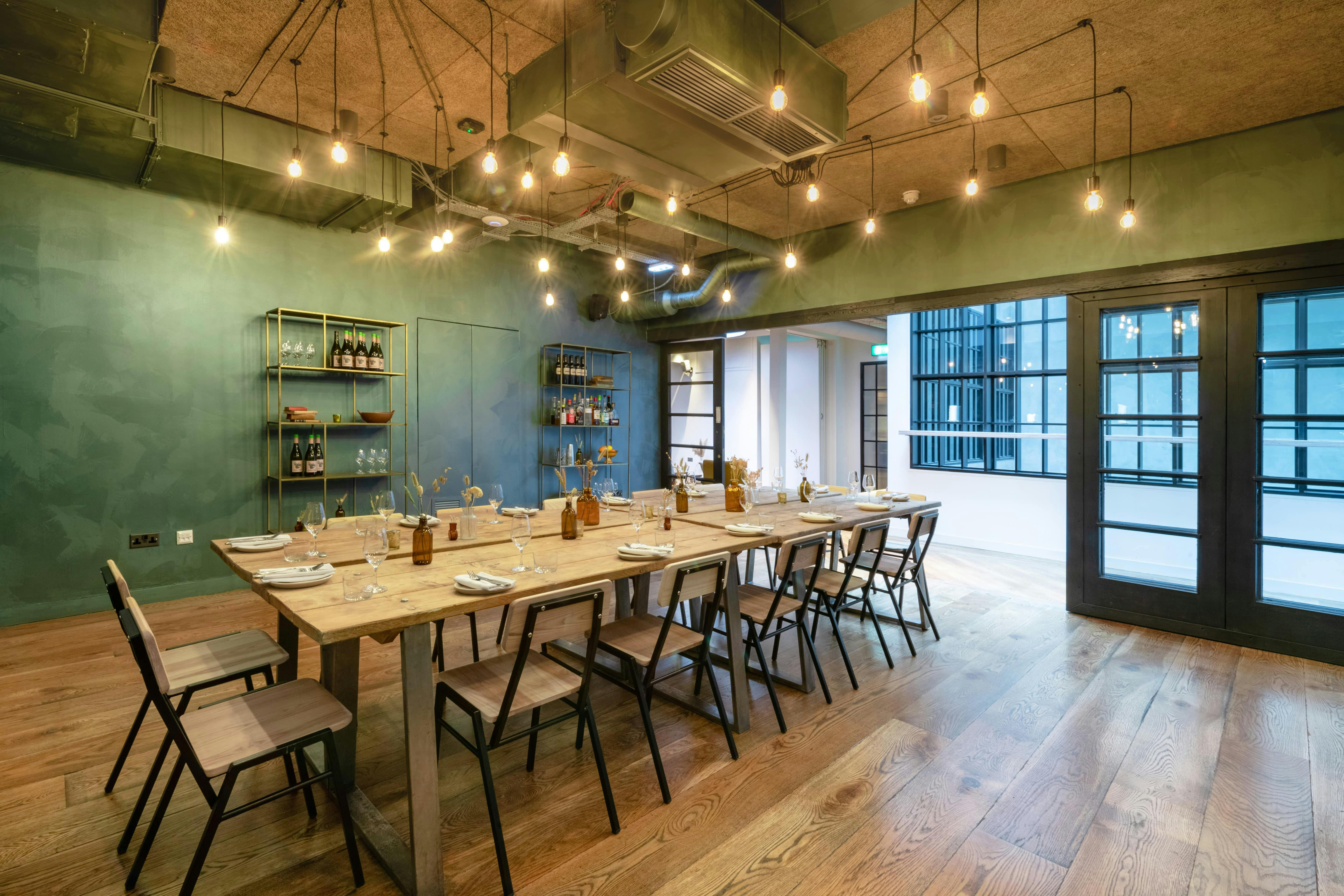 Stylish meeting space with wooden table and green walls, perfect for workshops and team meetings.