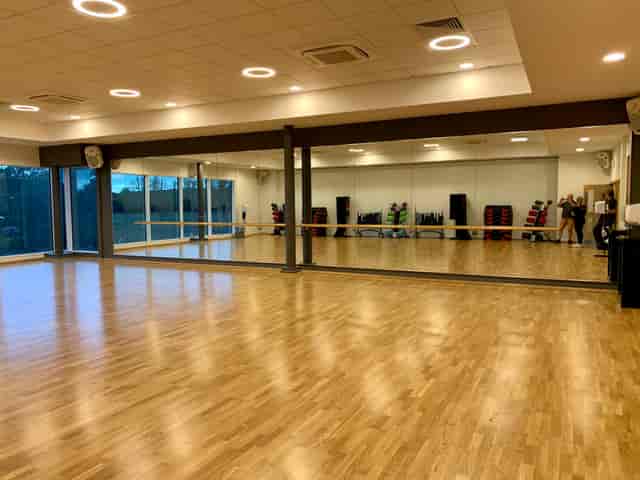 Spacious gym with polished floors and mirrors, perfect for dance classes and fitness events.