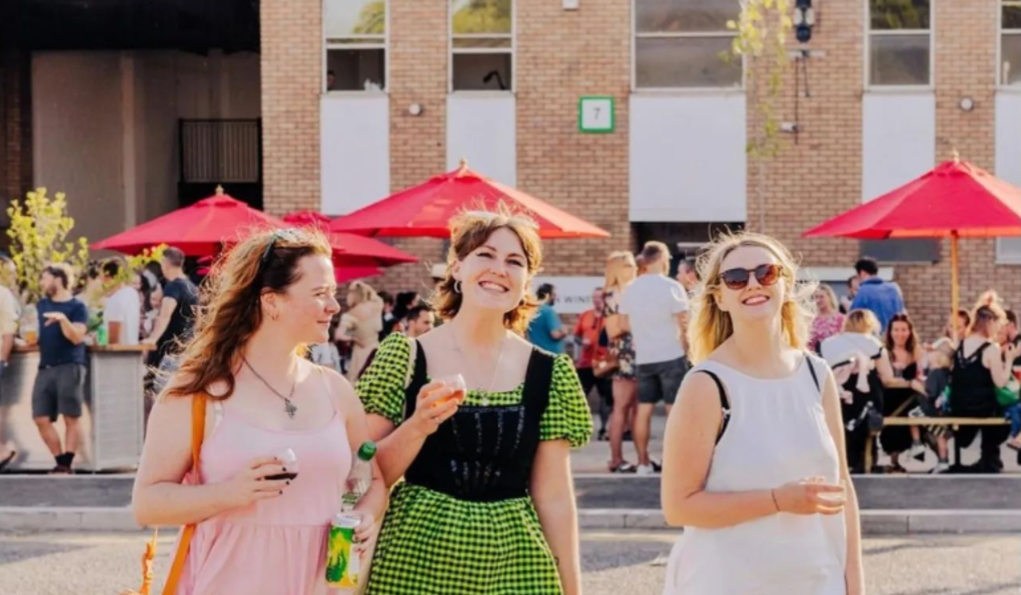 Vibrant outdoor event at Renegade Urban Winery with red umbrellas and smiling attendees. - Banner
