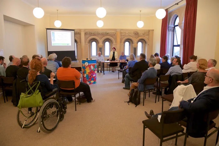 Meeting Room in St Peter's Church, Eaton Square, with attendees engaged in a presentation. - Banner