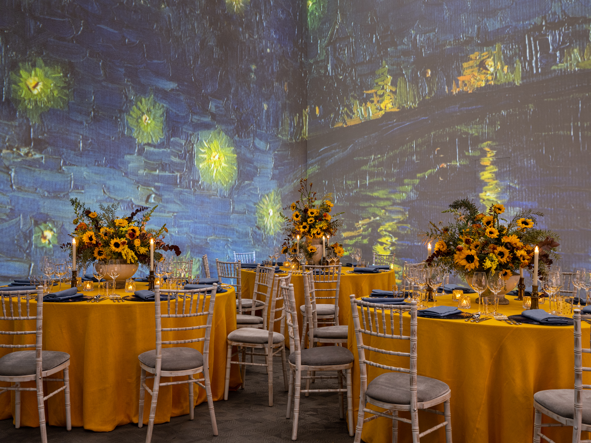 Elegant event space with yellow table linens and starry night backdrop for upscale gatherings.
