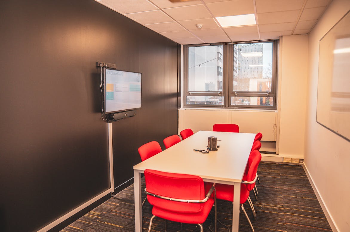 Modern meeting room with sleek table and red chairs, ideal for team brainstorming sessions.