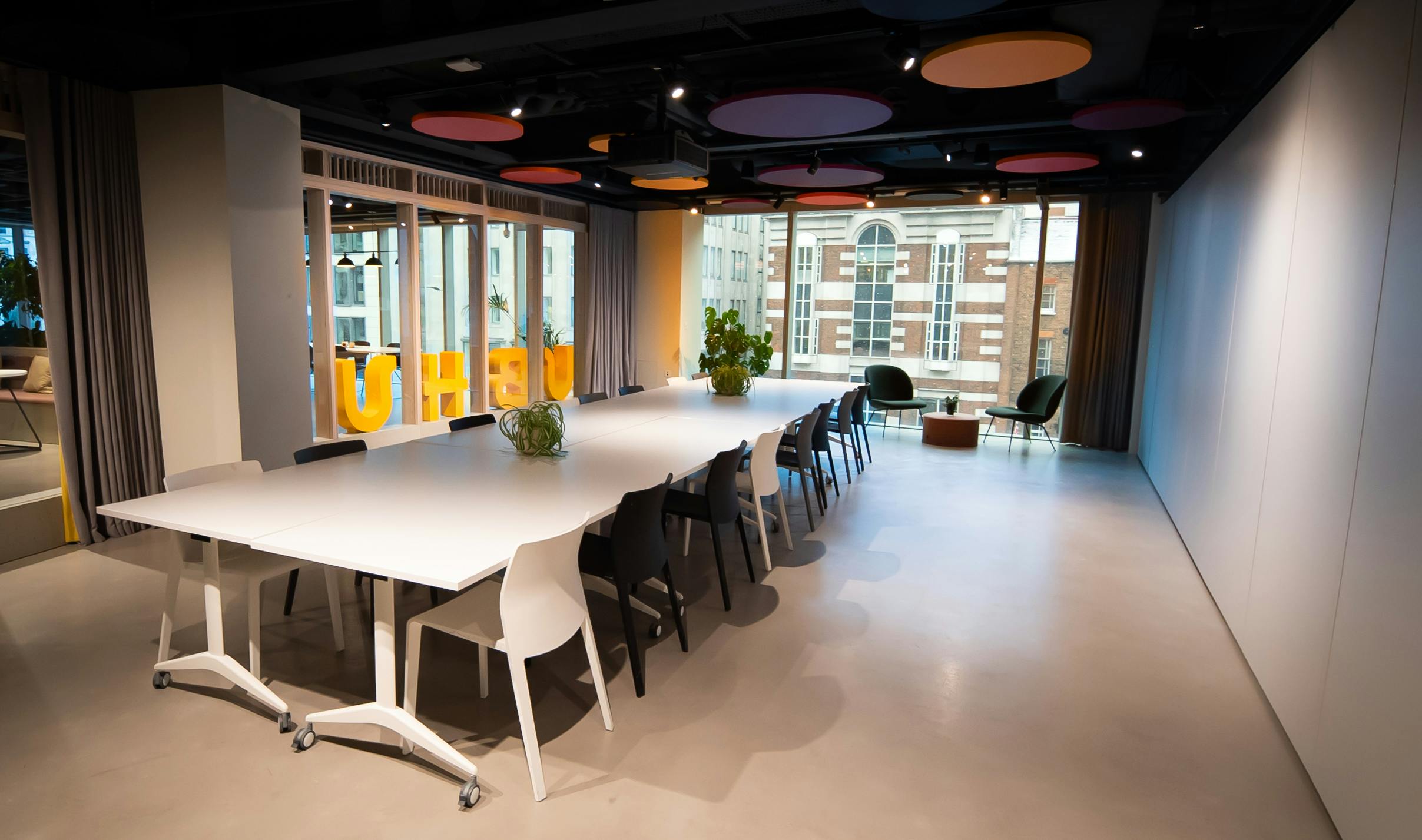 Modern meeting room with white table and vibrant ceiling for creative collaboration.