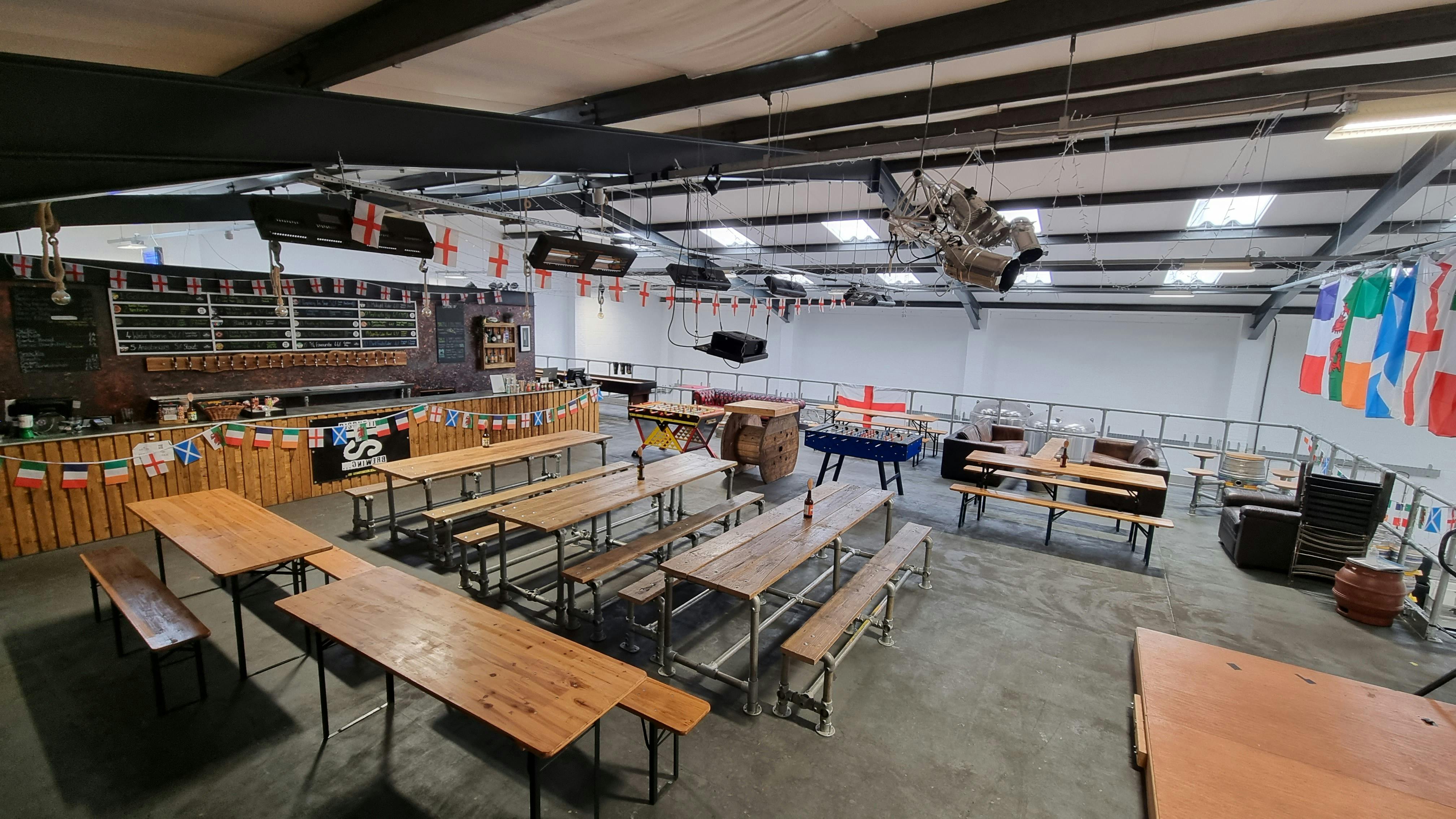 The Mezzanine at dISruption Brewery: festive event space with communal tables for gatherings.