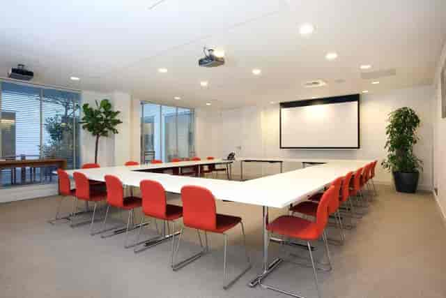 Modern meeting room with large table and red chairs, perfect for workshops and planning.