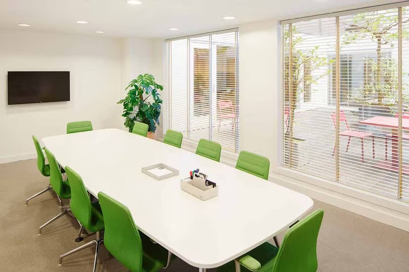 Modern meeting room with white table and green chairs, perfect for collaboration events.