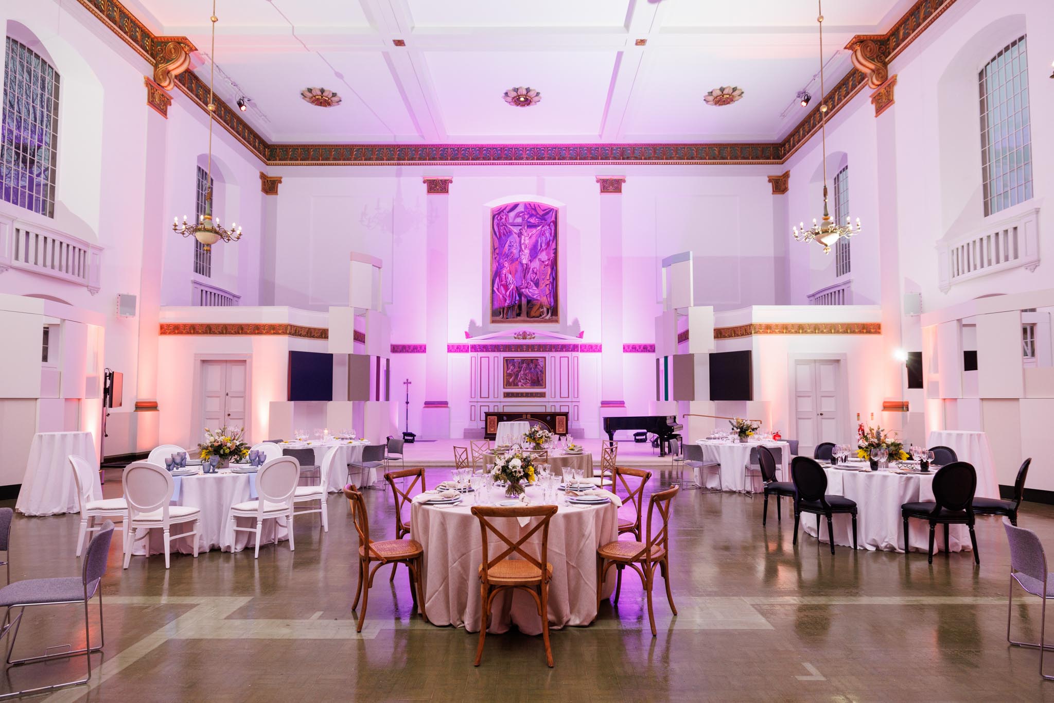 Elegant event space with floral centerpieces and purple uplighting for weddings and corporate events. - Banner