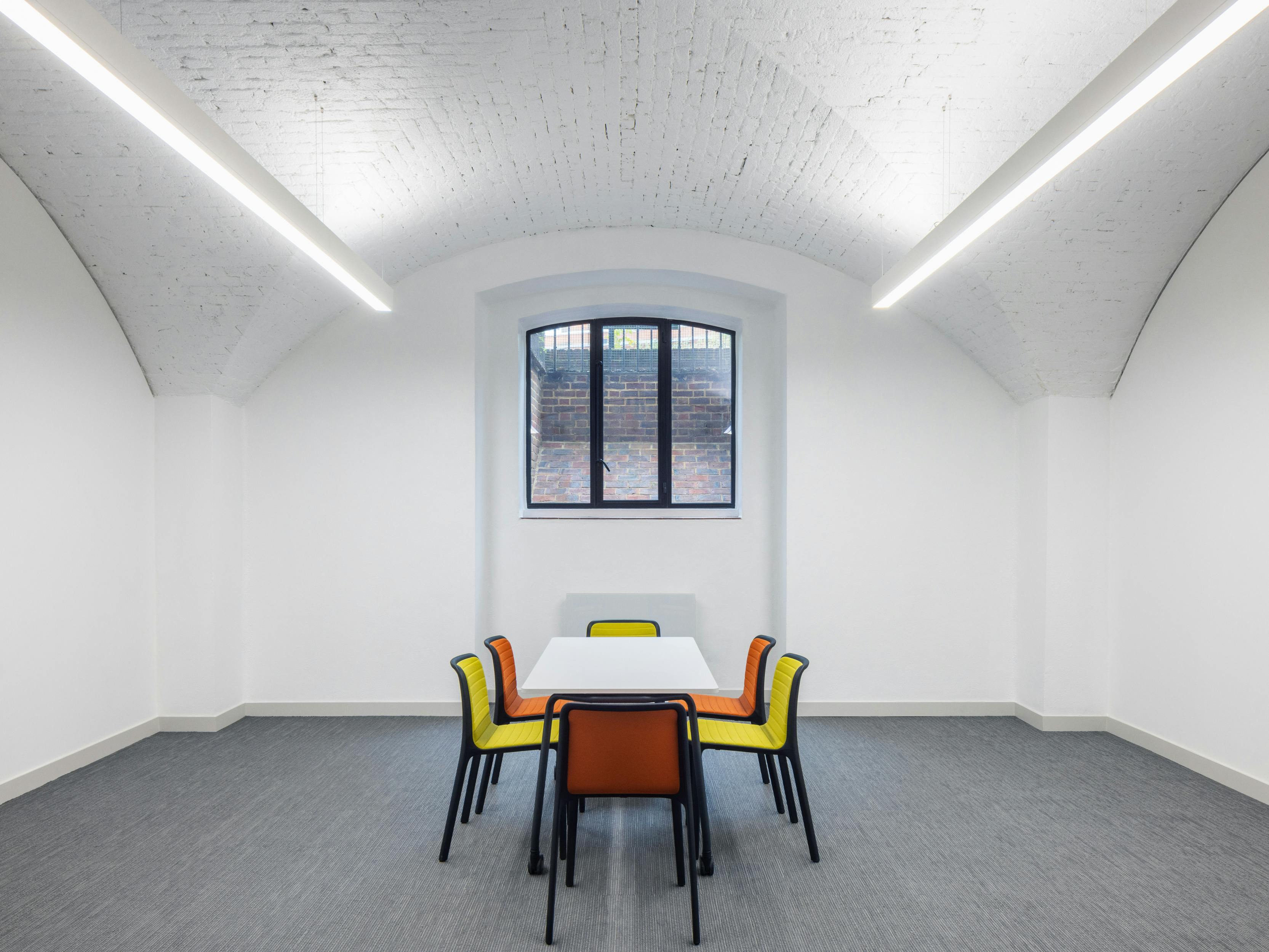 Versatile meeting space with large table and colorful chairs at St Johns, ideal for brainstorming.