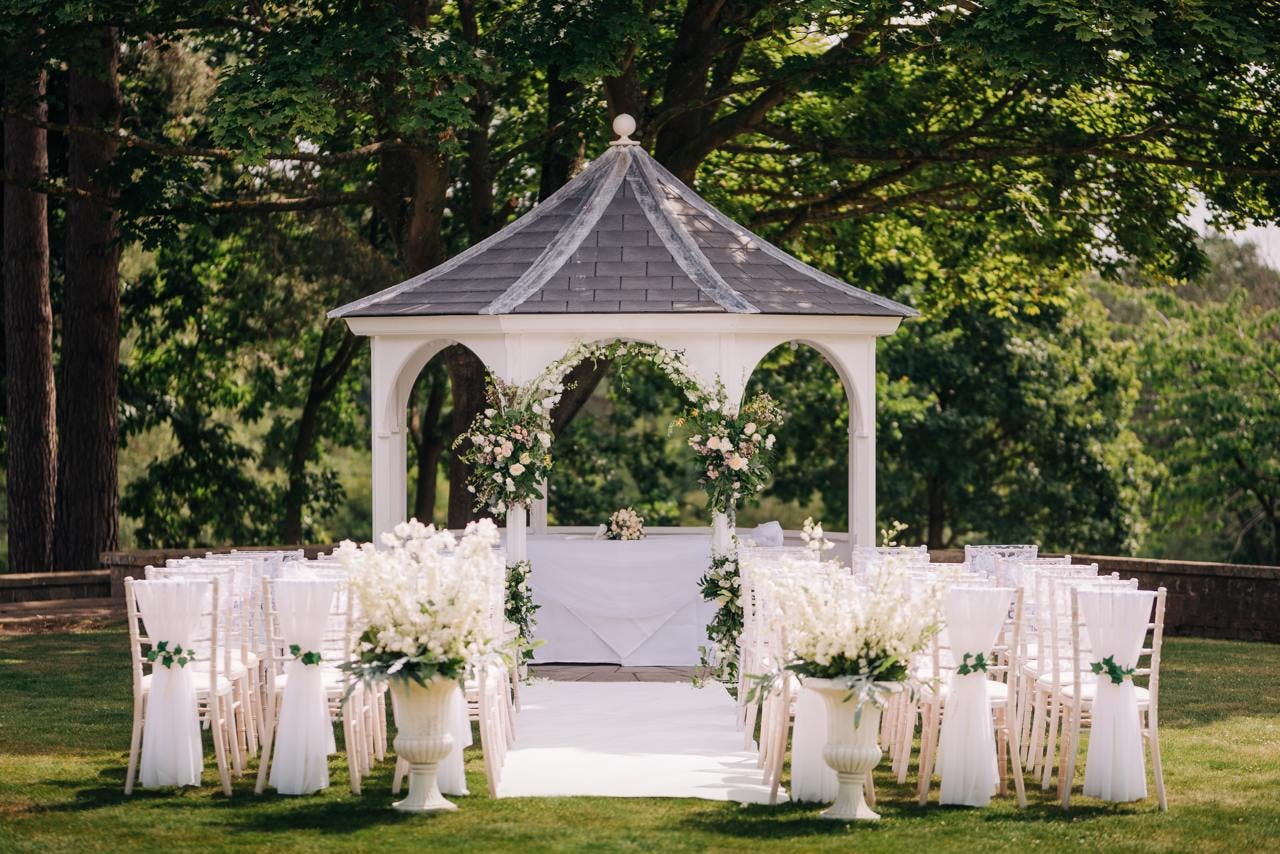 Outdoor wedding ceremony at The Orangery, featuring an elegant gazebo and floral decor.
