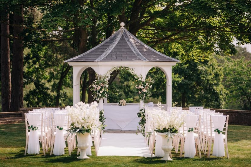 Outdoor wedding ceremony at The Orangery, featuring an elegant gazebo and floral decor.