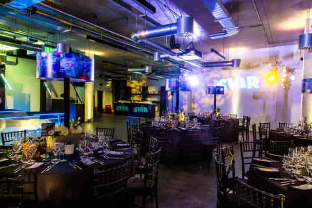 Industrial-chic event space with moody lighting set for a formal gala dinner.