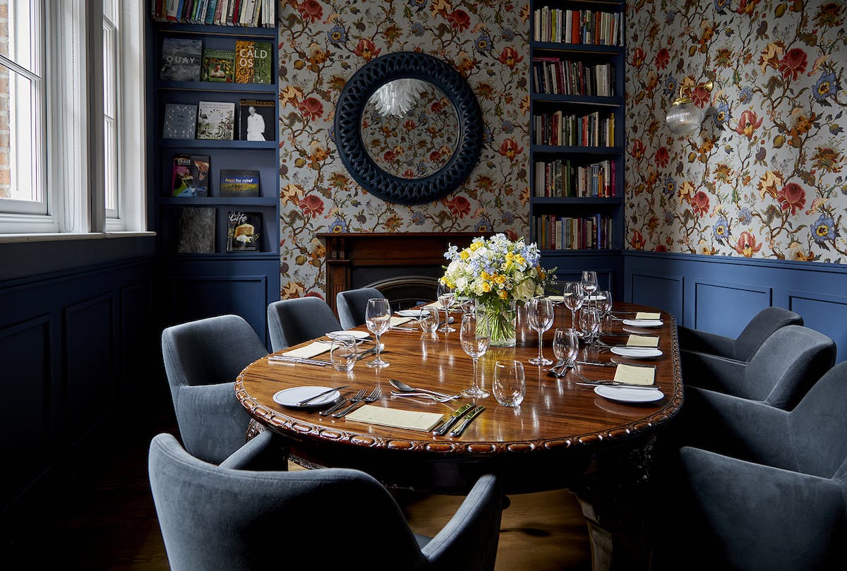 Elegant meeting room with round table, floral wallpaper for intimate gatherings.