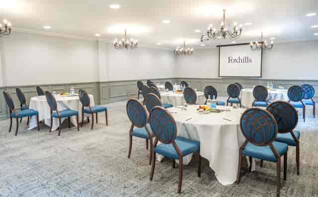 Corporate meeting room at Foxhills Library with round tables and elegant blue chairs.