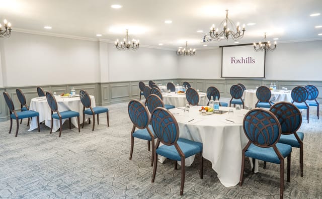Corporate meeting room at Foxhills Library with round tables and elegant blue chairs.
