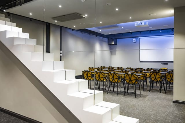 Modern meeting room with glass walls, ideal for workshops and corporate events.
