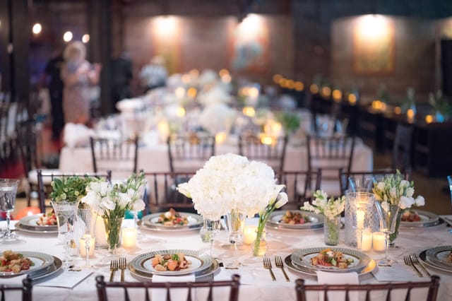 Elegant dining table with white floral centerpieces at Brooklyn Bowl event venue.