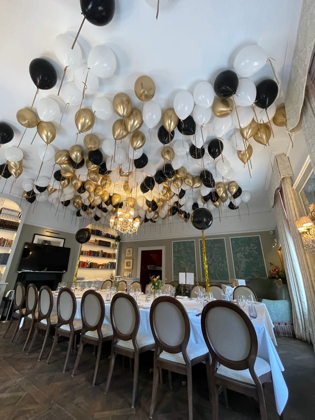 Elegant event space with black, white, and gold balloons for corporate gatherings.
