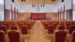 Spacious Sheraton Offenbach Hotel event hall with red chairs for conferences and presentations.