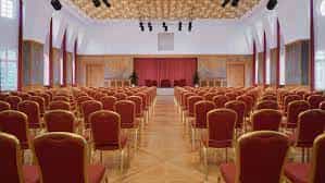 Spacious Sheraton Offenbach Hotel event hall with red chairs for conferences and presentations.