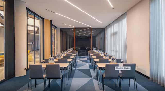 Modern meeting studio in Andaz Munich with natural light, perfect for corporate events.