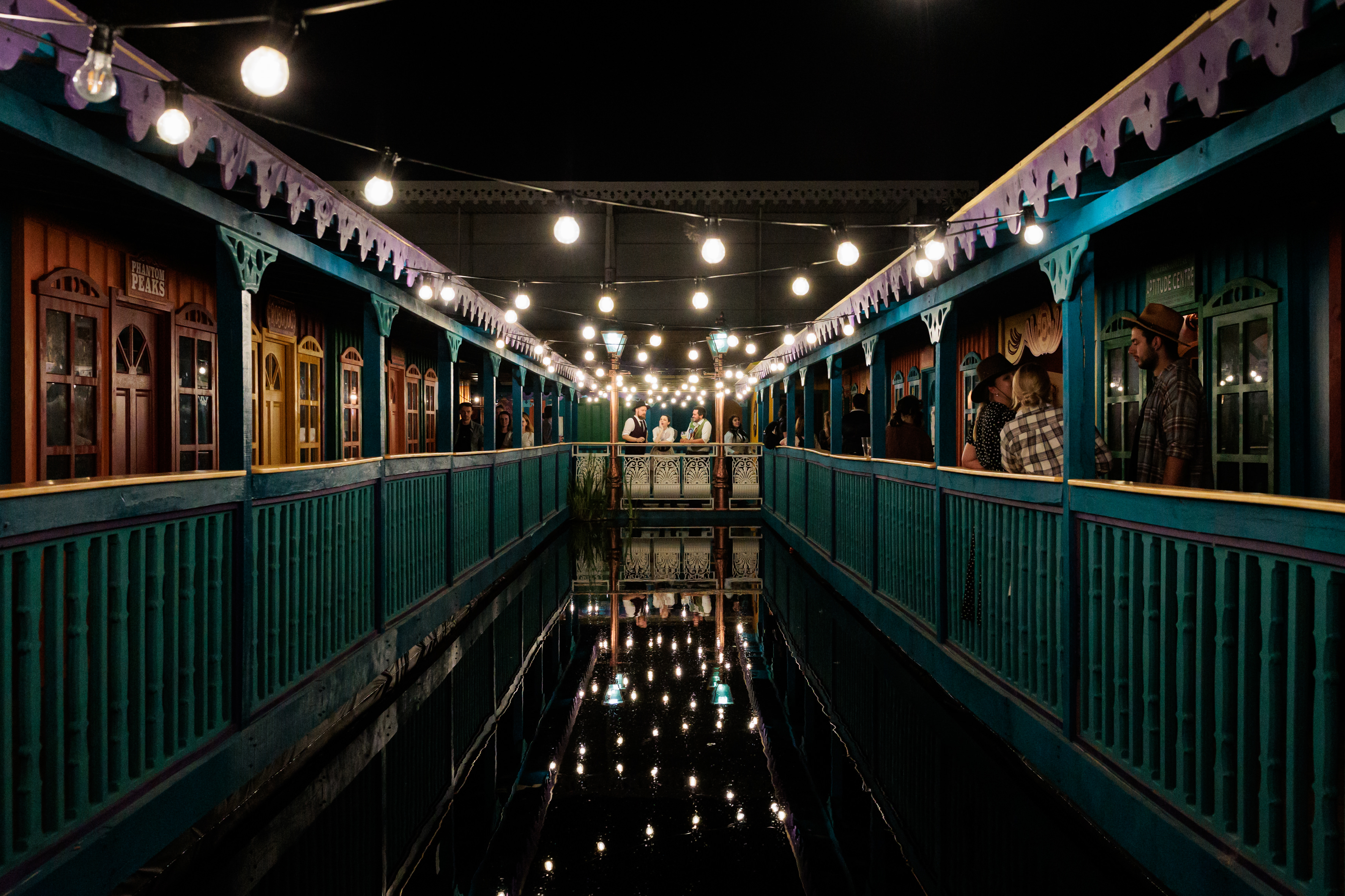 "Phantom Peak outdoor venue with colorful structures and string lights for evening events." - Banner