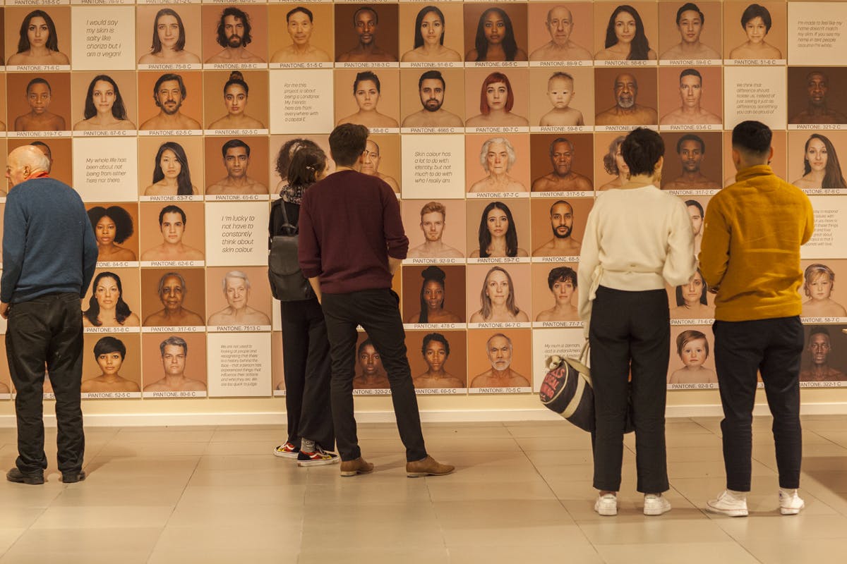 Diverse group at Migration Museum art installation promoting dialogue on diversity and community.