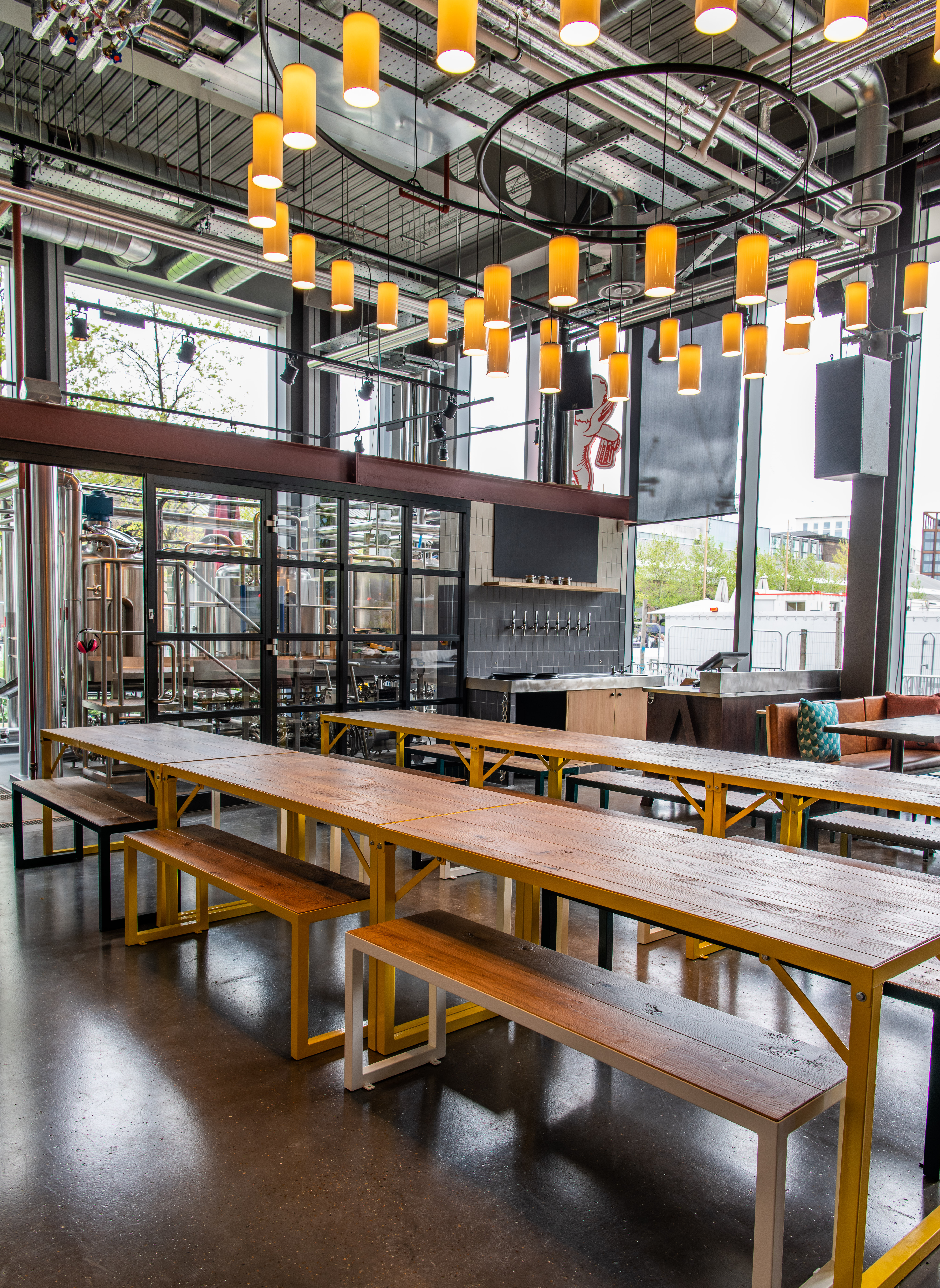 Modern industrial venue with communal tables for casual meetings and networking events. - Banner