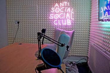 Modern podcasting studio with neon signage for media events and creative discussions.