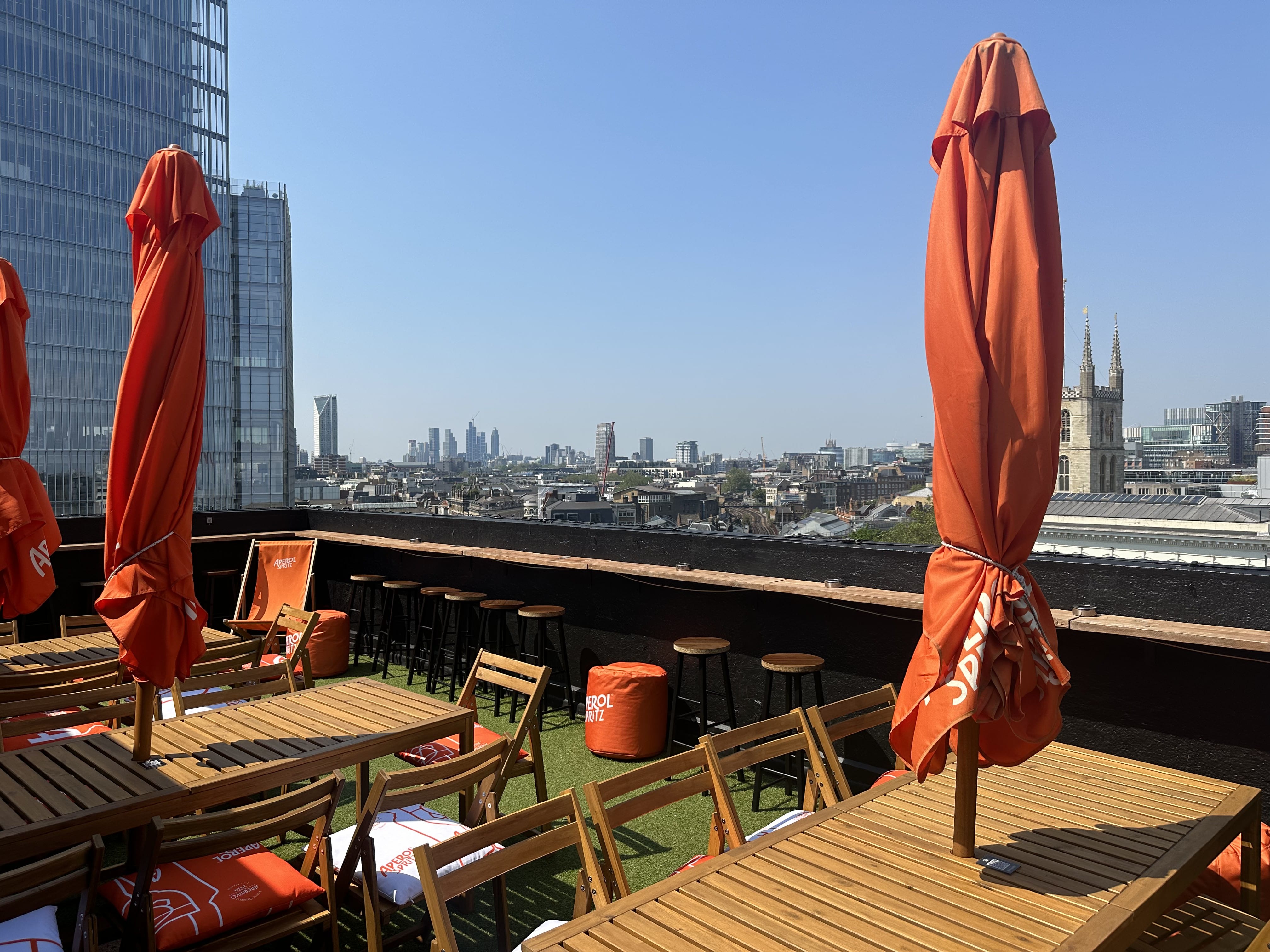 Vibrant London Bridge Rooftop with wooden furniture and skyline, ideal for outdoor events. - Banner