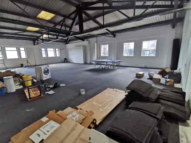Spacious unfinished event space with high ceilings, ideal for meetings and workshops.