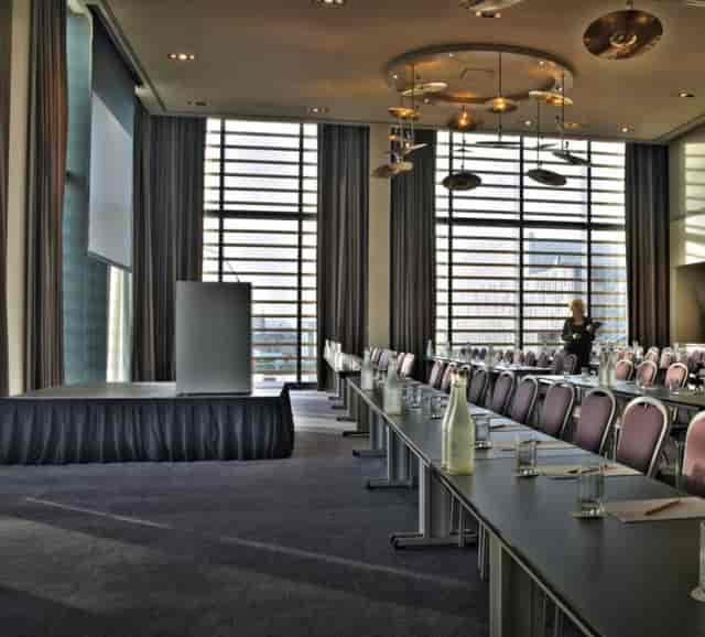 Modern meeting room with podium, tables, and natural light at The Gibson Hotel.