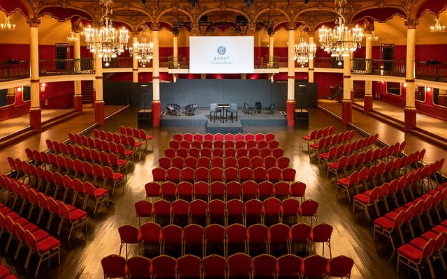 Elegant event space with tiered seating and chandeliers for conferences or galas.