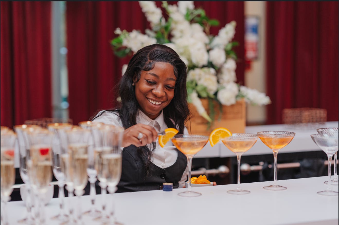 Bartender crafting cocktails at Livery Hall event with floral decor.