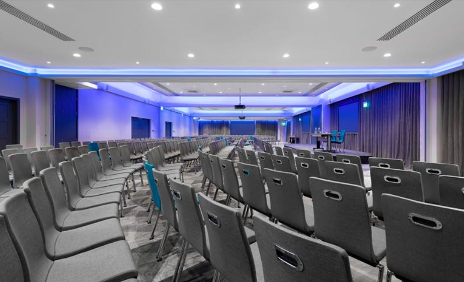Modern conference space at The Rosewood - Woodlands with gray chairs and AV equipment.