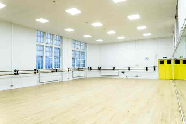 Spacious dance studio with wooden floors and large windows for creative workshops.