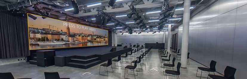 Modern event space with sleek stage and large screen for corporate presentations.
