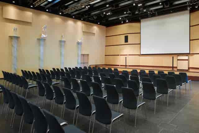 Millessalen event space with black chairs and projection screen for conferences and workshops.