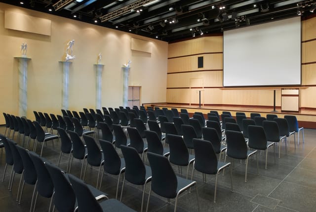 Millessalen event space with black chairs and projection screen for conferences and workshops.