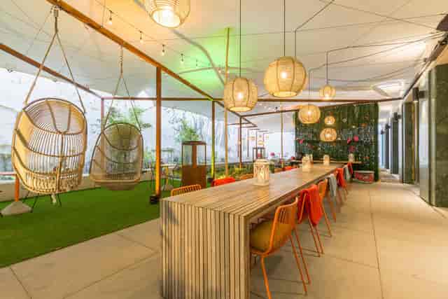 Stylish Urban Tent event space with wooden table, colorful chairs, and greenery.
