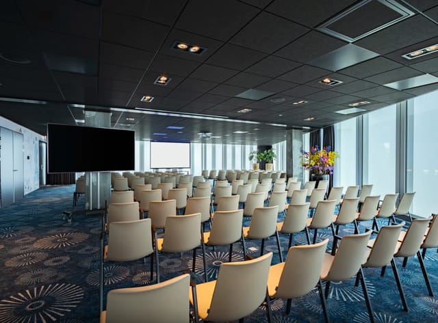 Modern conference room in NH Hotel Amsterdam with white chairs for corporate events.