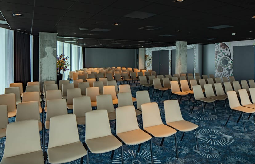 Meeting room in NH Hotel Amsterdam with beige chairs, ideal for conferences and workshops.