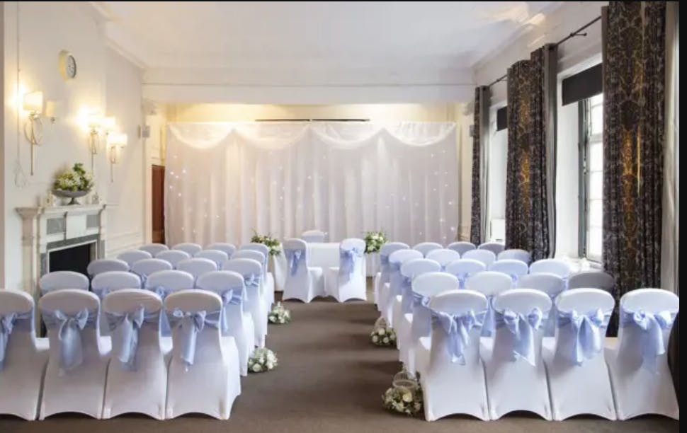 Wisteria event space with white chairs and blue sashes for weddings or corporate meetings.