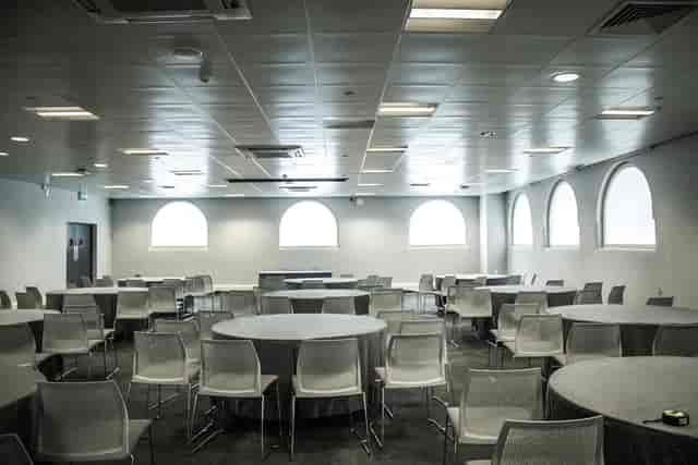 Versatile event space with round tables and natural light for meetings and gatherings.