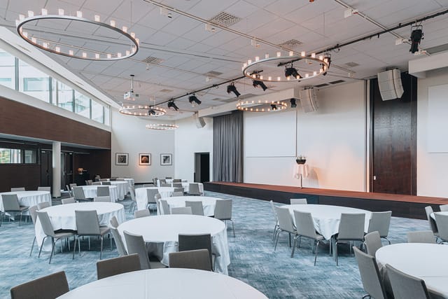 Spacious event venue with round tables and modern lighting in Courtyard by Marriott Stockholm.