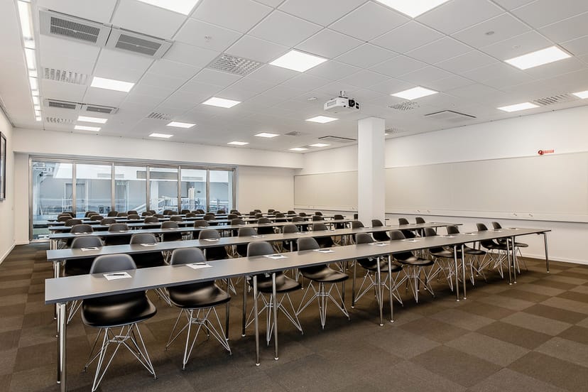 Conference room with tables and chairs, ideal for workshops and presentations.