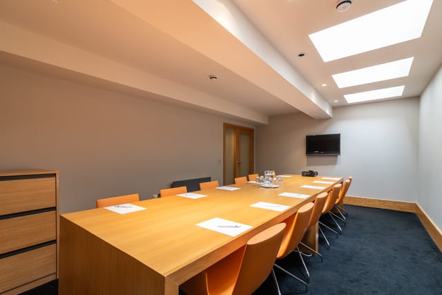 Modern conference room in Harrogate with wooden table and orange chairs for meetings.