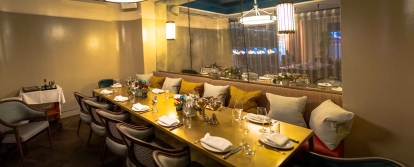Elegant semi-private dining room with gold table, ideal for corporate dinners and gatherings.